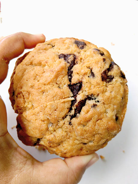 Close-up of Grandpa's hand holding his still-warm, yummy half-eaten homemade chocolate chip and nut cookie which Grandma has just baked.