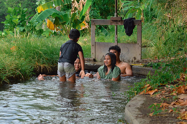 istock Young boy stands in water while mother reclines nearby in stream 2235302877