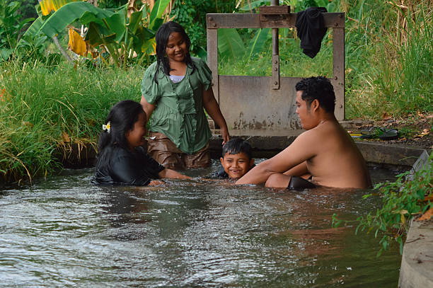 istock Boy prepares to dive through parents+?G??G?? linked hands in irrigation stream 2235302893