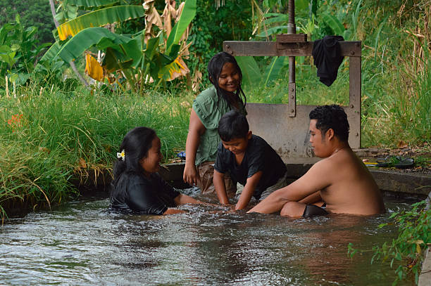 istock Young boy holds both parents+?G??G?? hands while playing in irrigation water 2235302894
