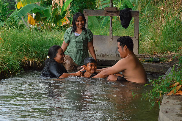 istock Son emerges proudly between parents+?G??G?? joined hands in irrigation stream 2235302905