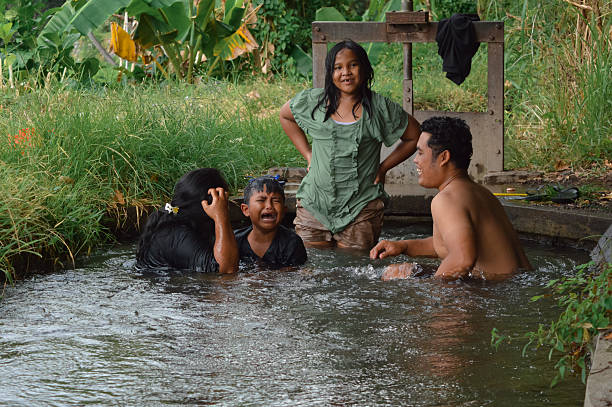 istock Young boy pretends to cry while family laughs during water play 2235302922