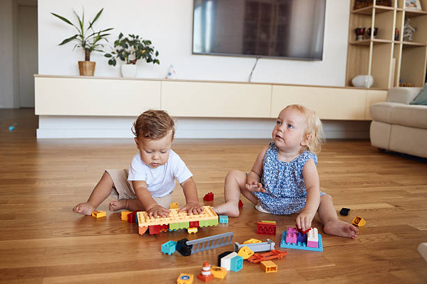 Playful kids enjoying the day. Small boy and girl playing with blocks indoors.