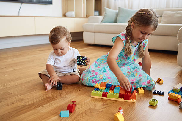 Playful kids enjoying the day. Small boy and girl playing with blocks indoors.