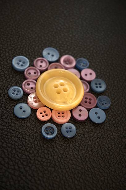High angle view of a buttons and sewing push pins against brown background