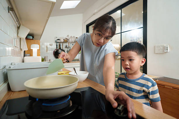 istock Asian mother and son stand together at the stove, preparing ingredients while smiling and talking, enjoying their kitchen time. 2235312708