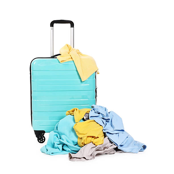 istock Suitcase and pile of different messy clothes isolated on white 2235322705