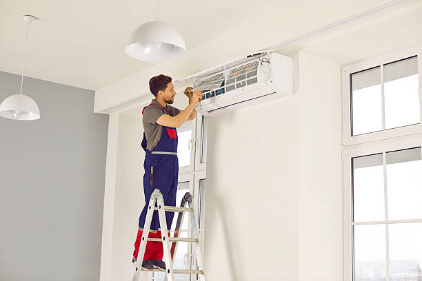 istock Technician standing on ladder installing or fixing modern air conditioner on white wall 2235324356