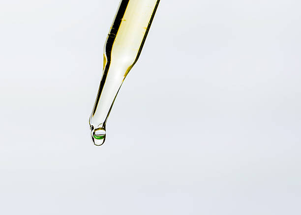 istock Drop of liquid serum falling from glass pipette on white background with copy space. 2235324898