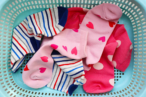 istock Mixed colorful socks with polka dot, stripe, and heart patterns in a laundry basket. 2235327044