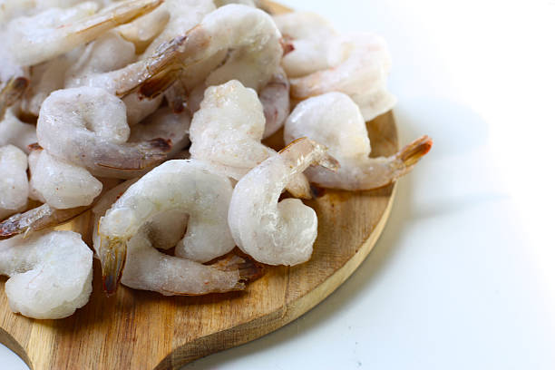 istock Frozen shrimps on wooden board. 2235328480