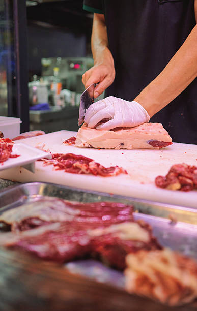 A chef carefully slicing fresh beef at a butcher's counter in a professional kitchen setting