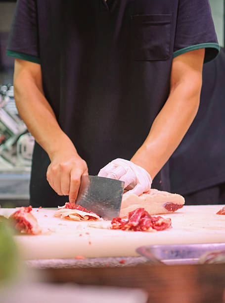 istock A chef is carefully slicing raw meat on a cutting board in a professional kitchen setting 2235329206