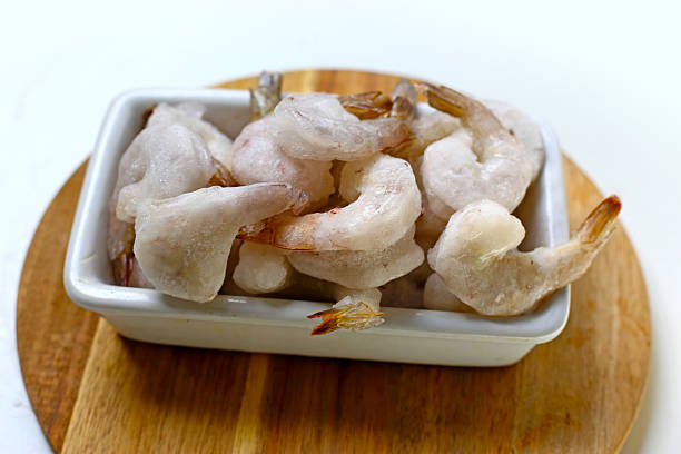 istock Frozen shrimps in a white bowl on wooden board. 2235330067