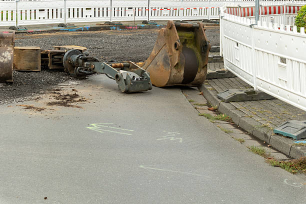 Excavator bucket and other equipment left on the ground at urban construction site