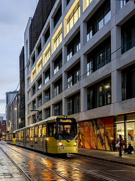 Evening view along a street in the centre of Manchester, UK. People can be seen on the promenade.