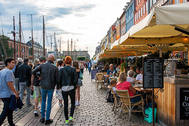 Nyhavn, Copenhagen, Denmark - 2 August 2025 Crowds stroll along a lively waterfront promenade with outdoor dining options.