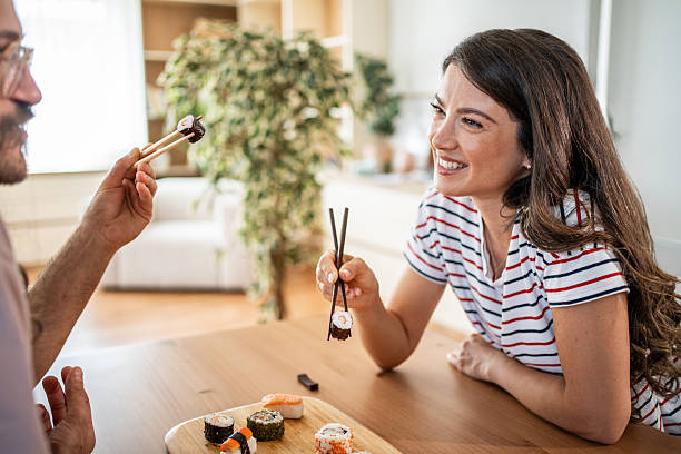 istock Happy couple sharing sushi in their modern apartment 2235349821