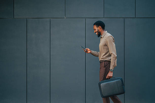 Businessman walking and using smartphone in urban setting