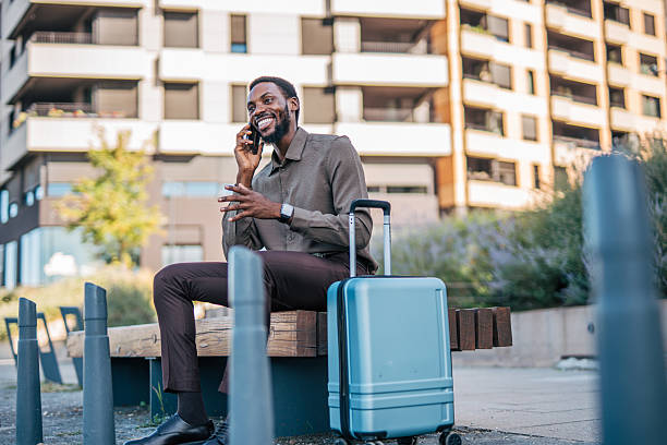 istock Businessman talking on phone while waiting with luggage 2235354379
