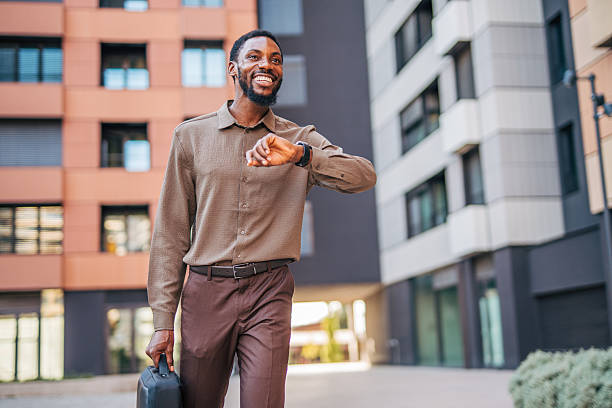 Smiling businessman checking time while walking near office building