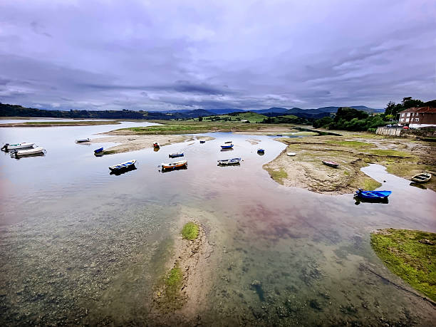Boats waiting floating in the low tide in the estuary of the Pombo river, at San Vicente de la Barquera, in Cantabria, North Spain