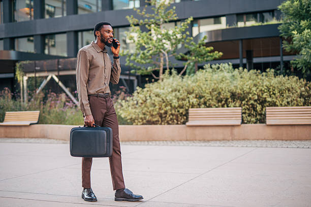 istock Businessman walking and talking on phone outside office 2235354738