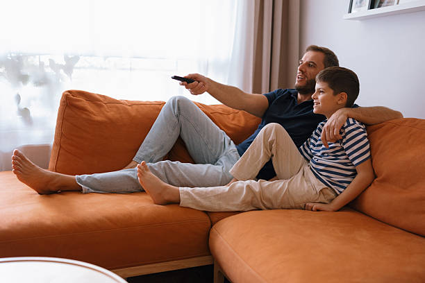 istock Father and son relaxing and watching TV on the sofa 2235354811