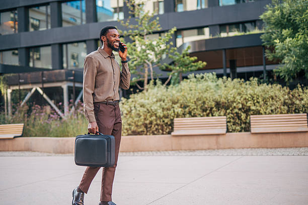 istock Businessman walking and talking on phone outside office 2235354894