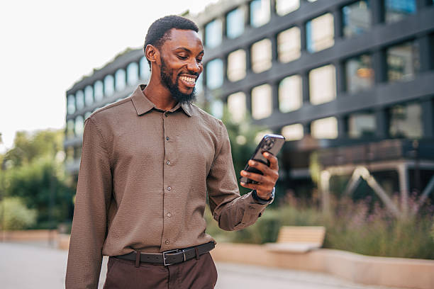 istock Smiling businessman using smartphone while walking near office building 2235355438