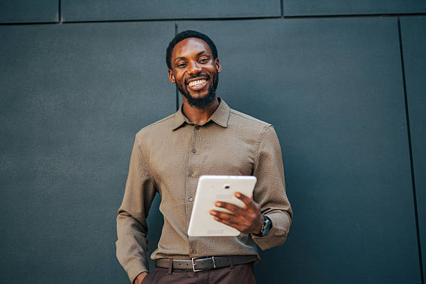 istock Smiling businessman using digital tablet in front of modern office building 2235355466