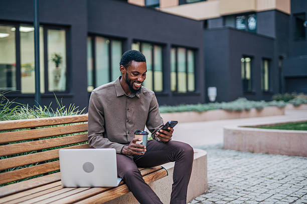istock Businessman using smartphone and drinking coffee outdoors 2235355785
