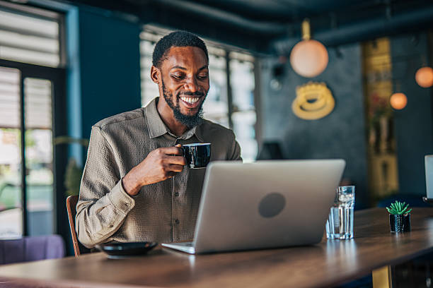 istock Young businessman drinking coffee and working on laptop in cafe 2235355957