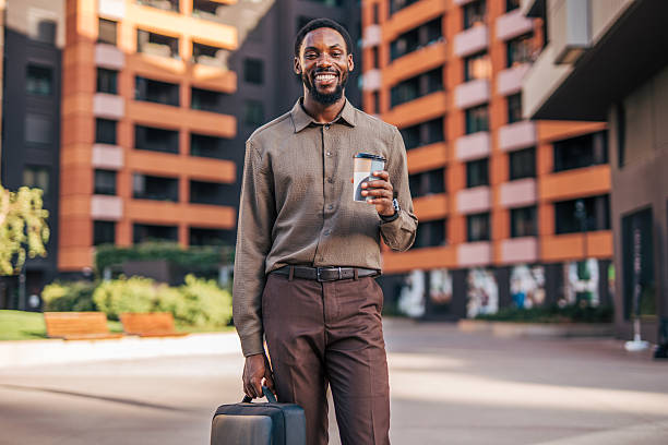 istock Smiling businessman walking with coffee and briefcase in urban setting 2235356210