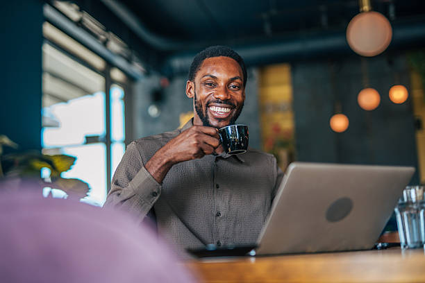 istock Smiling freelancer enjoying coffee while working on laptop in cafe 2235356278