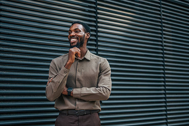 istock Smiling businessman leaning against modern building exterior 2235356671