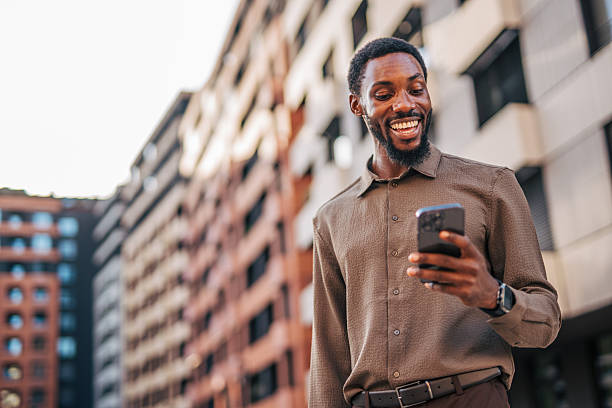 istock Smiling businessman using smartphone while walking in the city 2235356837