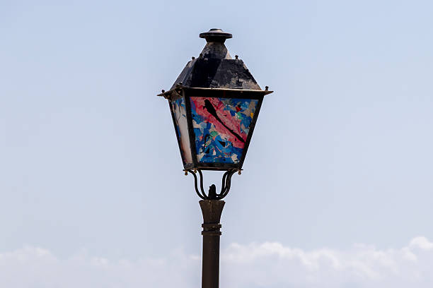 A vintage lamppost stands against a clear blue sky, featuring vibrant colors and patterns that evoke creativity and artistic expression. An ideal backdrop for urban art themes.