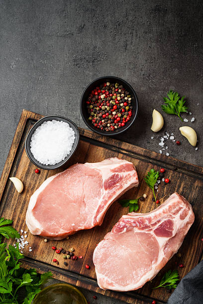 istock Raw pork steak. Fresh meat on cutting board with spices. 2235357410