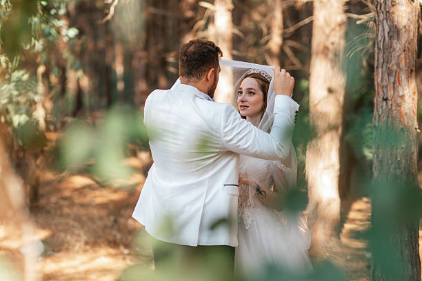 Groom lifting brides veil during wedding ceremony in forest. High quality photo