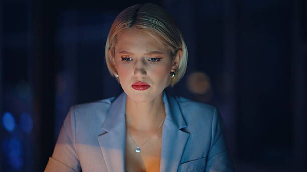 Night manager drinking coffee tired of overload at workplace portrait. Fatigued businesswoman massaging temples suffering from pressure at dark office. Overworked woman checking mobile phone time