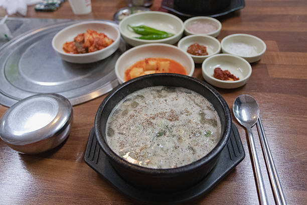 Asian woman enjoying Korean kimchi soup and tableful of side dishes