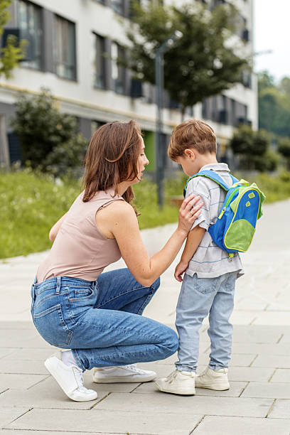 istock Mother comforting sad child with backpack outside school 2235362815