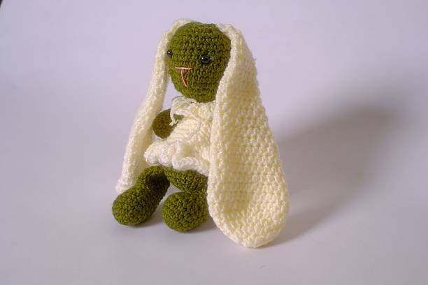 istock Knitted bunny doll with green body and long cream ears. 2235366307