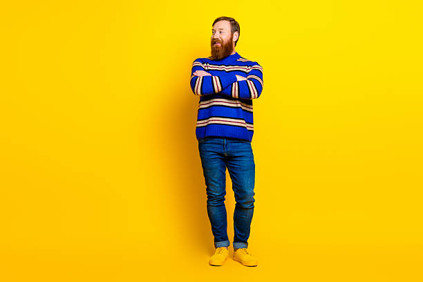 istock Casual man with beard in colorful attire standing confidently against a solid yellow background in a modern pose 2235367951