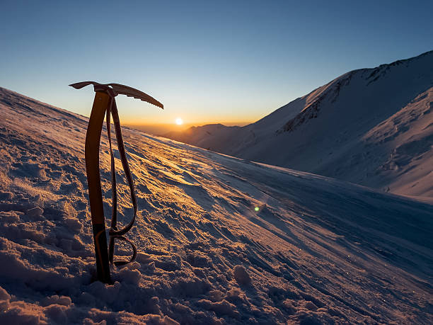 Summit push day beginning with incredible sunrise during Extreme expedition under famous Lenin peak (Ibn Sina Peak) 7134m. High altitude view with climber's ICE AXE stuck into snow morning landscape