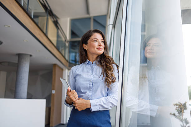 istock Businesswoman holding digital tablet looking out office window 2235371065