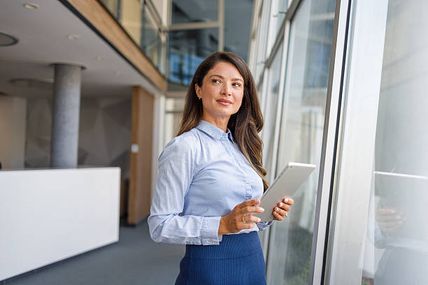 istock Businesswoman holding digital tablet looking out office window 2235371104