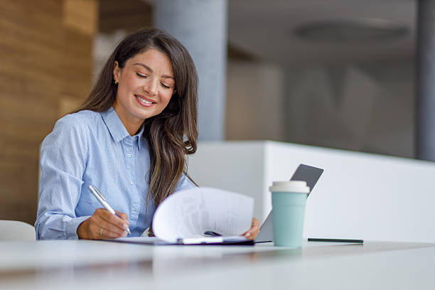 istock Businesswoman working at her desk, taking notes and smiling 2235371114