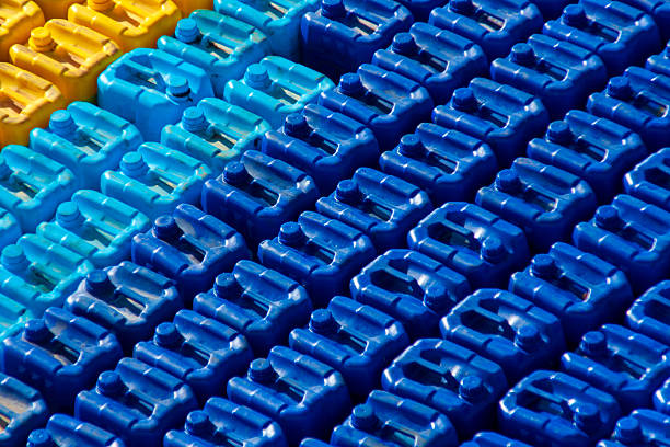 Stacked plastic jerrycans in blue, light blue, and yellow colors create a bold geometric pattern and abstract industrial background